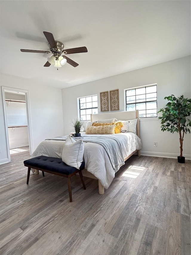 bedroom with a ceiling fan, baseboards, and wood finished floors