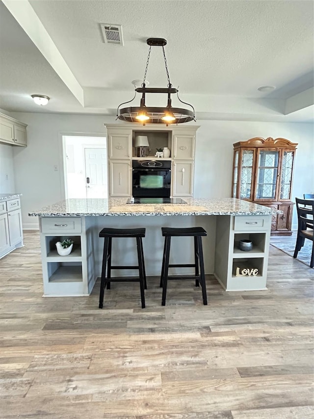 kitchen with light wood finished floors, visible vents, oven, and open shelves