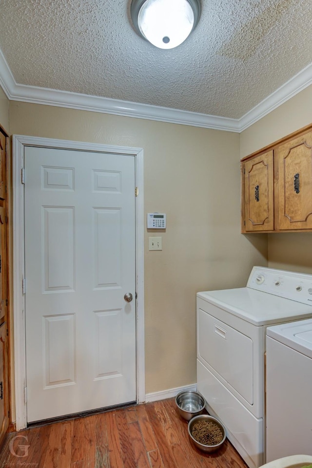 washroom with crown molding, washing machine and dryer, light wood-style flooring, cabinet space, and a textured ceiling