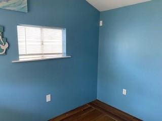 unfurnished room featuring vaulted ceiling and dark wood-style flooring