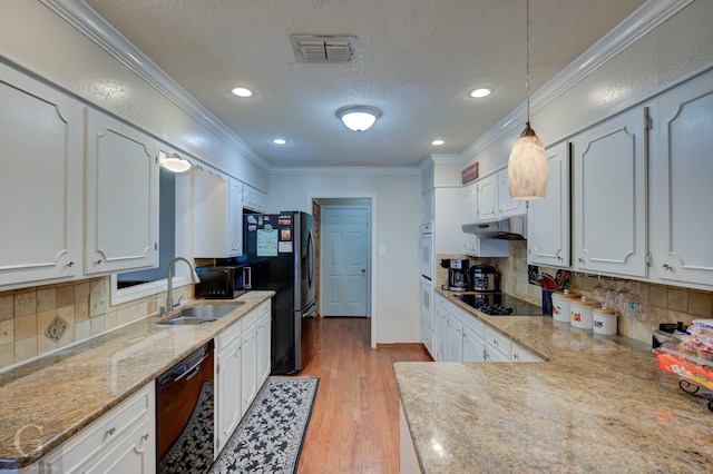 kitchen featuring visible vents, under cabinet range hood, ornamental molding, black appliances, and a sink