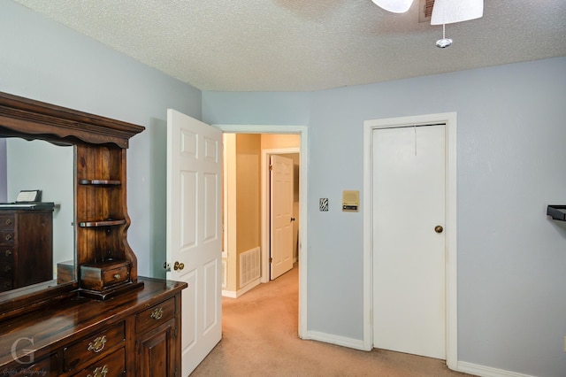 bedroom with visible vents, baseboards, light colored carpet, and a textured ceiling