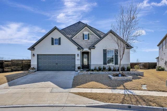 french country home with stone siding, brick siding, concrete driveway, and fence