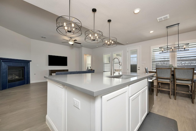 kitchen featuring a glass covered fireplace, light wood-type flooring, visible vents, and a sink