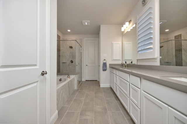 full bathroom with double vanity, a garden tub, a stall shower, and a sink