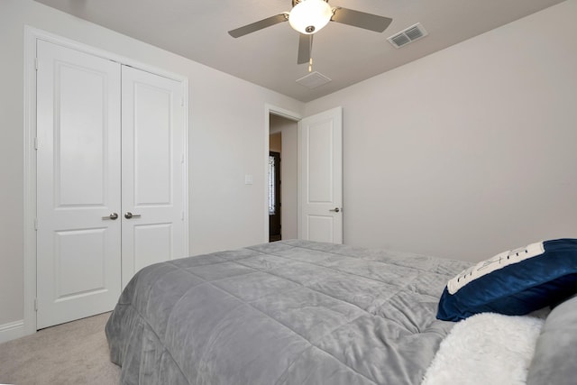 carpeted bedroom featuring visible vents, a closet, and ceiling fan