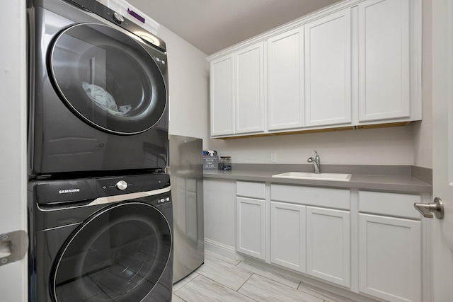 laundry room featuring cabinet space, stacked washing maching and dryer, and a sink