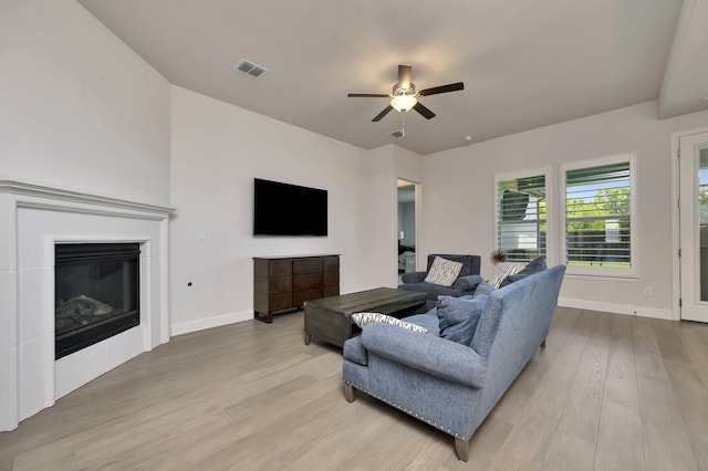 living room with light wood-type flooring, ceiling fan, baseboards, and visible vents