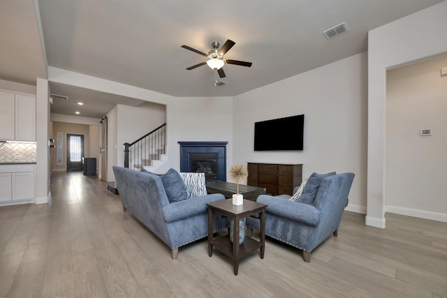 living room featuring visible vents, ceiling fan, baseboards, and light wood-style floors