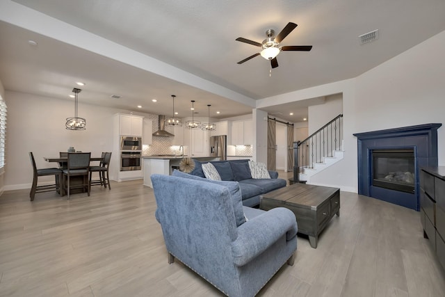 living room with visible vents, a barn door, light wood-style floors, and baseboards