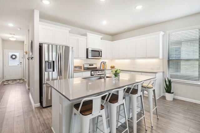 kitchen featuring backsplash, appliances with stainless steel finishes, a breakfast bar, and a sink