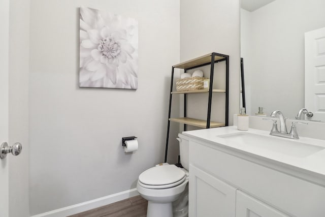 bathroom featuring toilet, vanity, baseboards, and wood finished floors