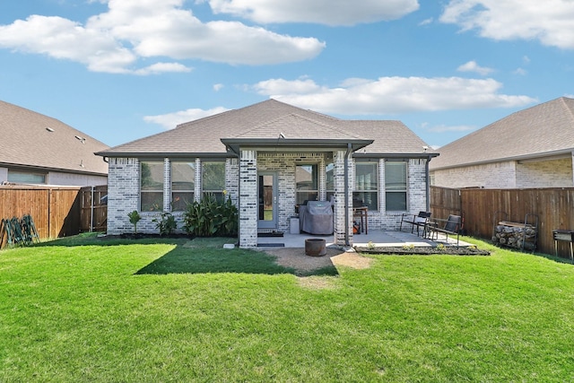 rear view of property with a fenced backyard, a lawn, brick siding, and a patio