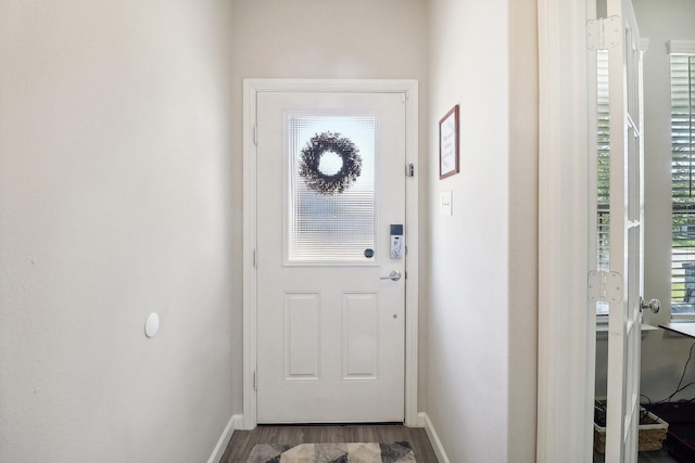 doorway featuring baseboards and wood finished floors