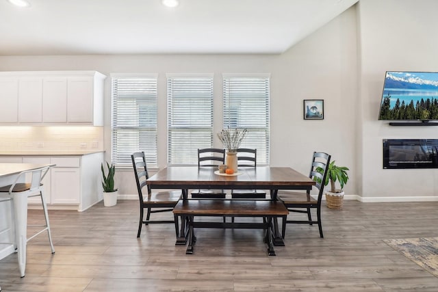 dining area featuring a glass covered fireplace, recessed lighting, light wood-type flooring, and baseboards