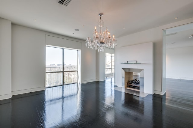 unfurnished living room with visible vents, baseboards, a fireplace with flush hearth, an inviting chandelier, and wood finished floors