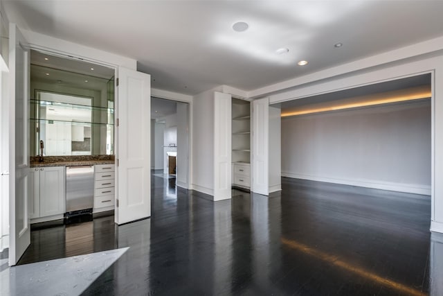 unfurnished room with dark wood finished floors, a fireplace, and baseboards