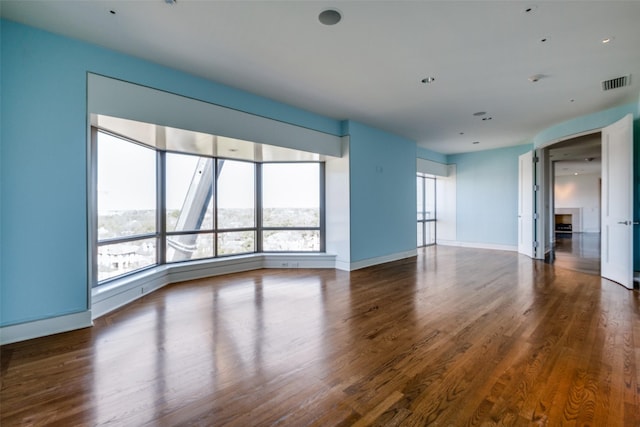 unfurnished living room featuring wood finished floors, visible vents, and baseboards