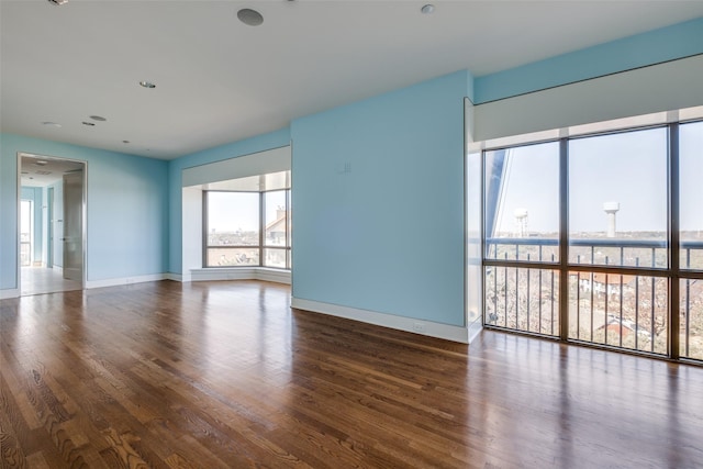 spare room with baseboards and wood finished floors