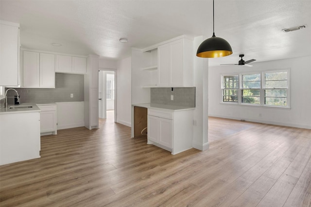 kitchen featuring a sink, visible vents, open shelves, and light wood-style flooring