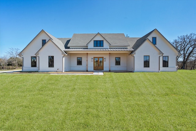 view of front of home featuring a front yard, a standing seam roof, a shingled roof, french doors, and metal roof