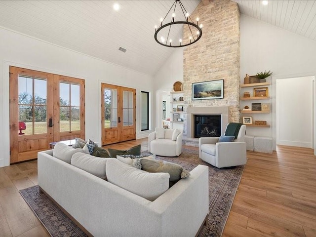 living room featuring french doors, a stone fireplace, wood finished floors, and wooden ceiling