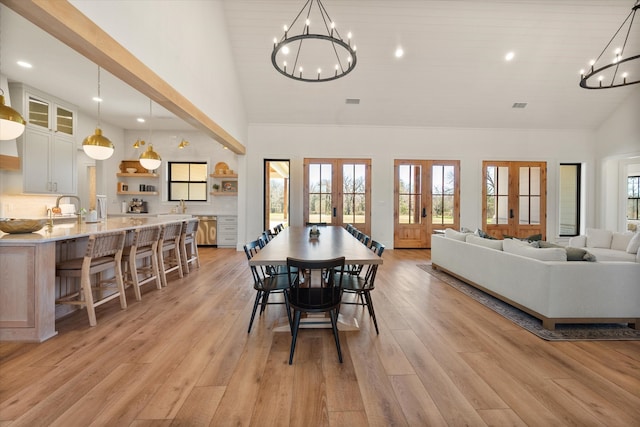 dining space with a wealth of natural light, french doors, a notable chandelier, and light wood finished floors