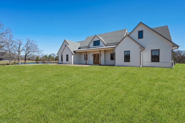 modern inspired farmhouse featuring brick siding, a standing seam roof, metal roof, and a front lawn