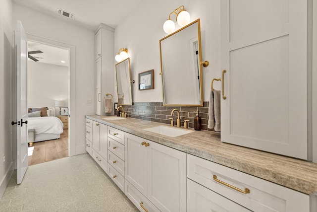 bathroom with double vanity, visible vents, backsplash, and a sink