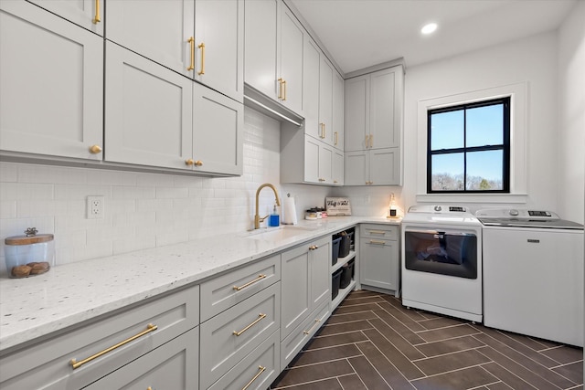 kitchen featuring light stone counters, tasteful backsplash, independent washer and dryer, and a sink