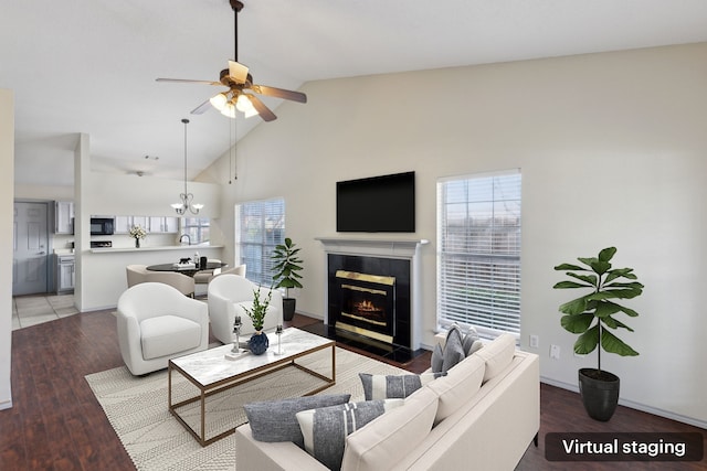 living room with a fireplace with flush hearth, ceiling fan with notable chandelier, high vaulted ceiling, and light wood-style floors