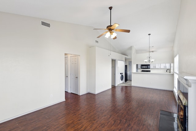 unfurnished living room featuring ceiling fan with notable chandelier, a fireplace, washer / clothes dryer, and wood finished floors