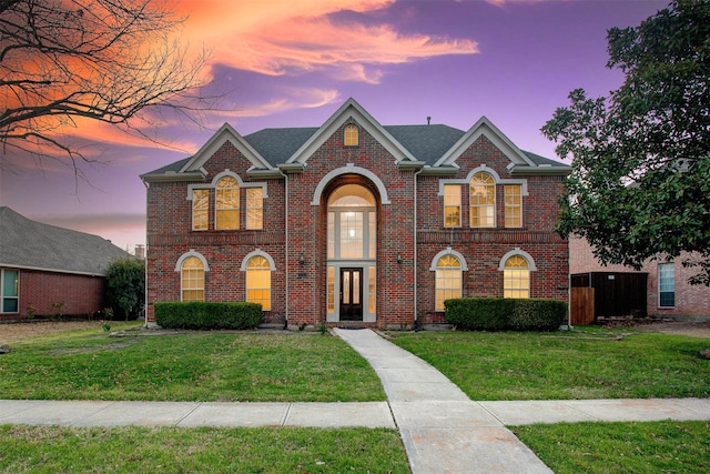 view of front facade with a lawn and brick siding