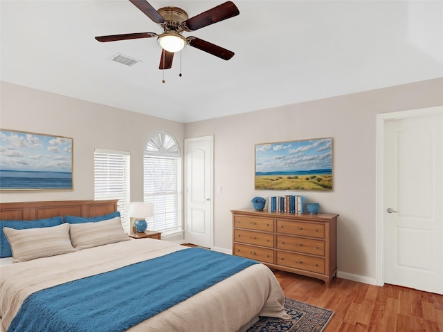 bedroom with a ceiling fan, light wood-style floors, visible vents, and baseboards