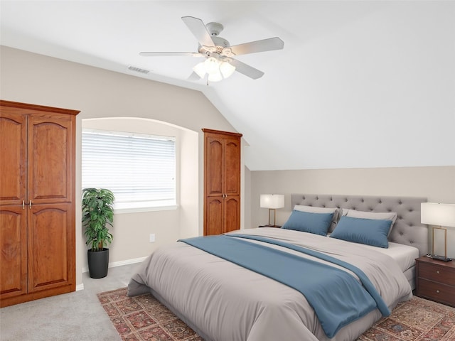 bedroom with a ceiling fan, baseboards, visible vents, lofted ceiling, and light carpet