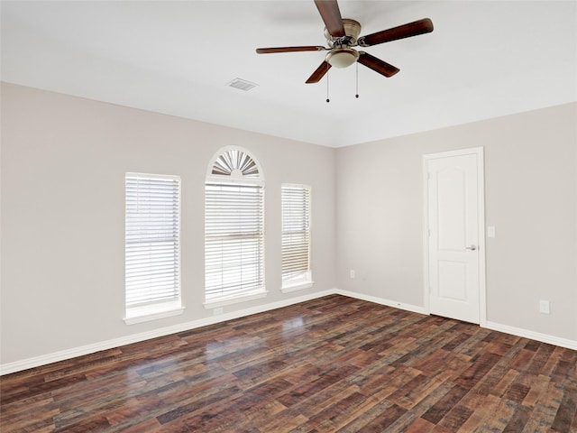 empty room with a ceiling fan, dark wood-type flooring, baseboards, and visible vents