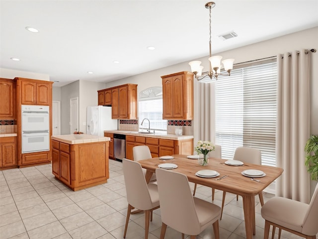 kitchen with tasteful backsplash, visible vents, tile counters, a chandelier, and white appliances