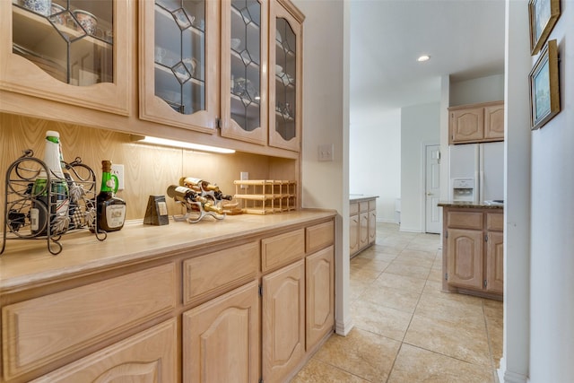 bar featuring light tile patterned floors, recessed lighting, white refrigerator with ice dispenser, and baseboards