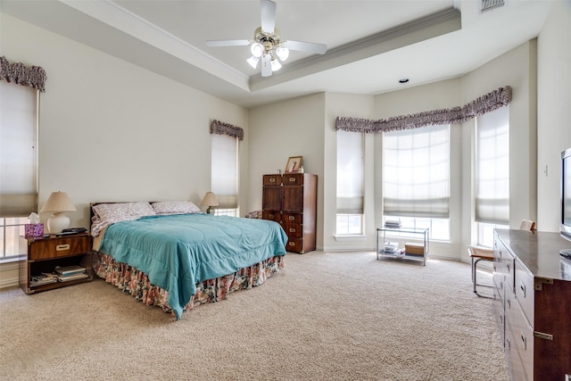 carpeted bedroom featuring baseboards, a ceiling fan, crown molding, and a tray ceiling