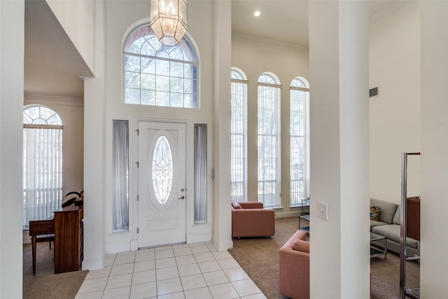 entryway featuring light tile patterned floors, visible vents, a towering ceiling, and ornamental molding