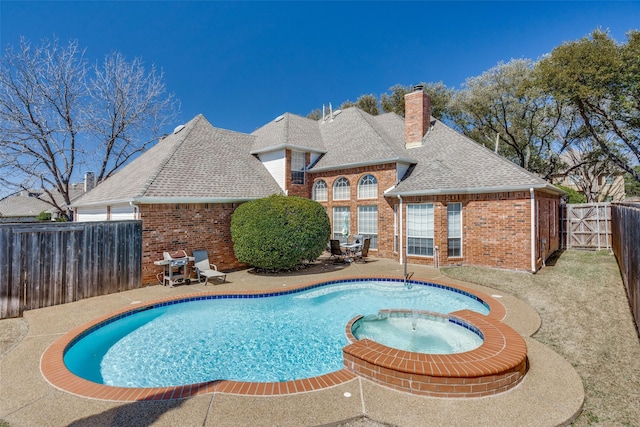 view of swimming pool featuring a pool with connected hot tub, a patio area, and a fenced backyard