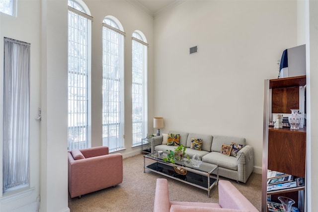 living room with visible vents, carpet floors, plenty of natural light, and ornamental molding