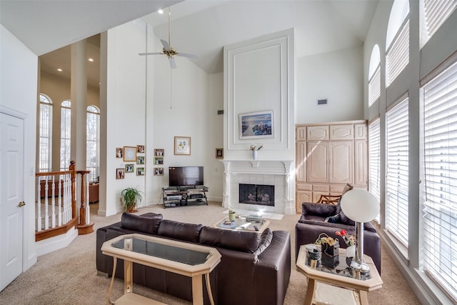 carpeted living area featuring a high ceiling, a healthy amount of sunlight, visible vents, and a tile fireplace