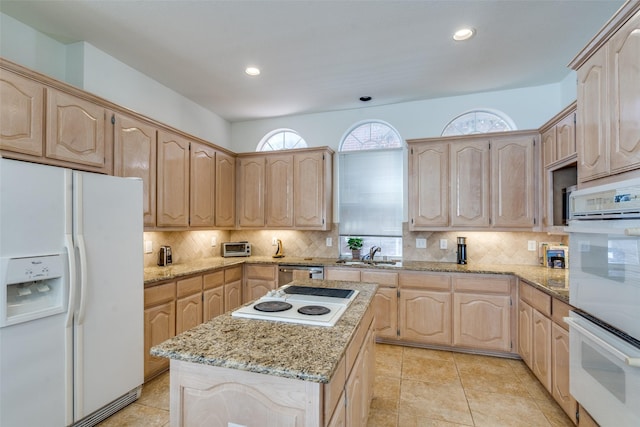 kitchen featuring white appliances, light stone countertops, backsplash, and light brown cabinetry