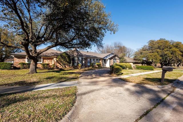 view of front of property with concrete driveway, brick siding, and a front lawn