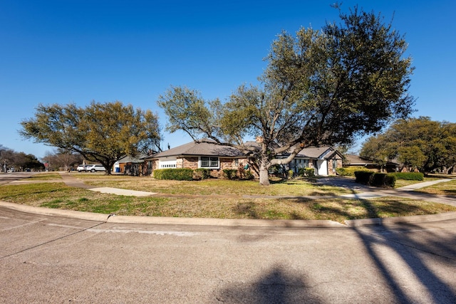 view of front of property with an attached garage, concrete driveway, and a front lawn