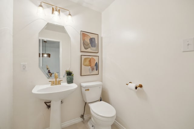 half bath featuring toilet and baseboards