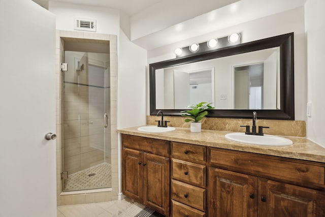 full bathroom with a shower stall, double vanity, visible vents, and a sink