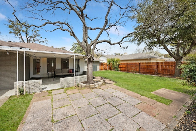 exterior space featuring a patio, an outdoor living space, a yard, a fenced backyard, and brick siding