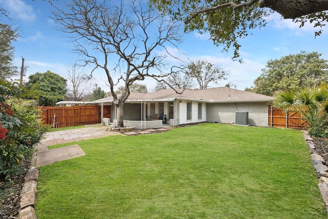 rear view of property featuring brick siding, a fenced backyard, a lawn, and a sunroom